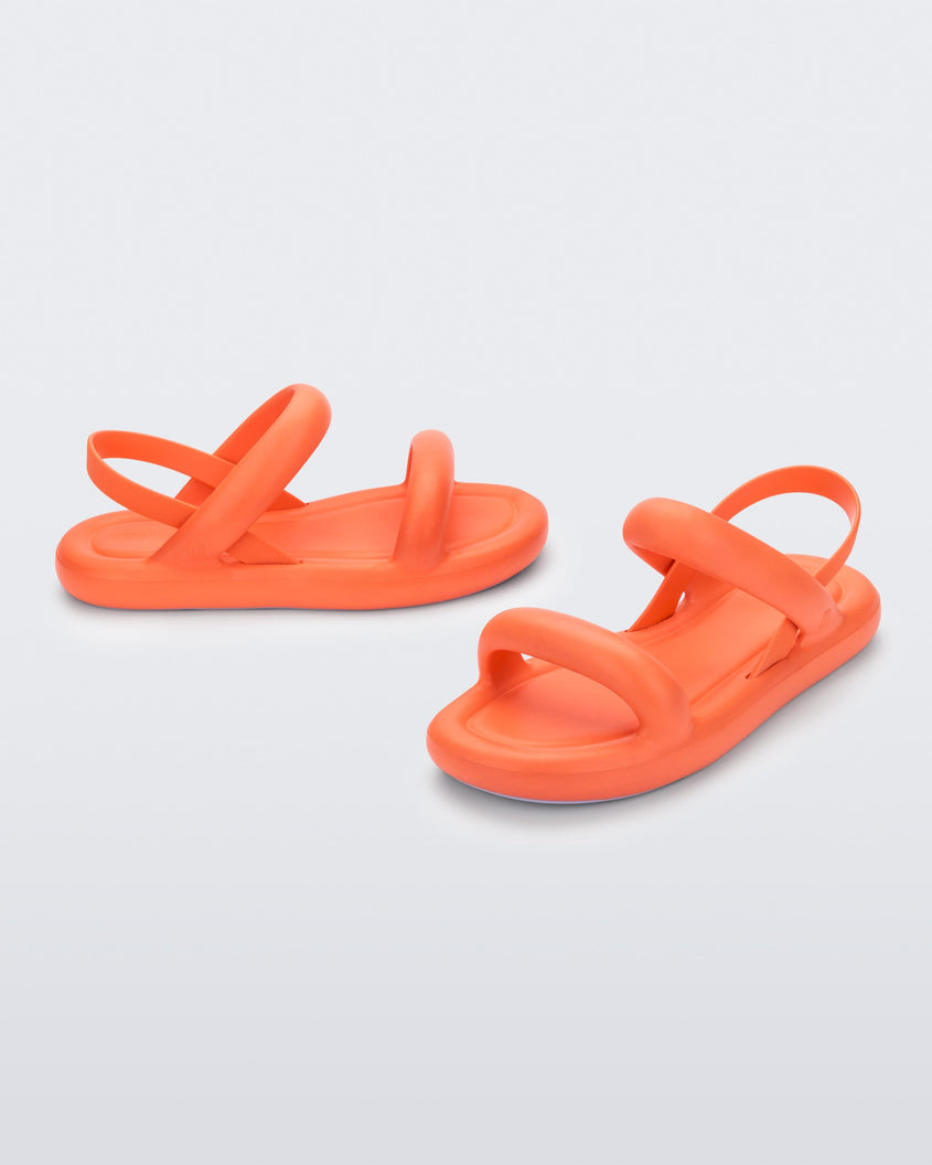 An angled side and front view of a pair of orange Melissa Free Bloom sandals with puffer-like straps.