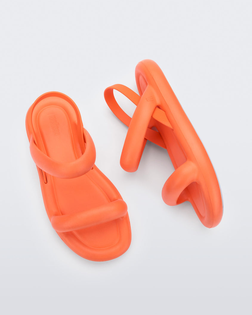 A top and side view of a pair of orange Melissa Free Bloom Sandals with puffer-like straps.