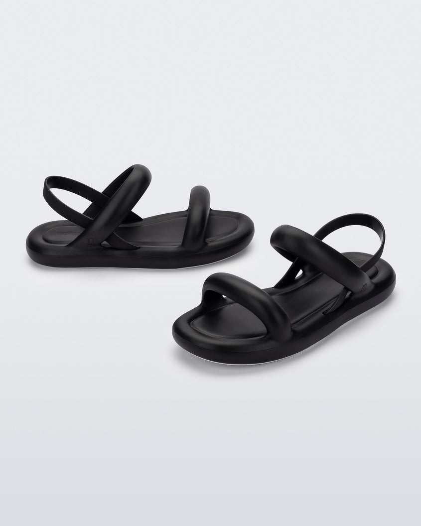 An angled side and front view of a pair of black Melissa Free Bloom sandals with puffer-like straps.