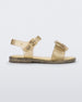 Side view of a gold glitter Mini Melissa Mar sandal with a bow.