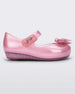 Side view of a pearly pink Mini Melissa Ultragirl flat with a top strap and a heart bow buckle detail on the toe.