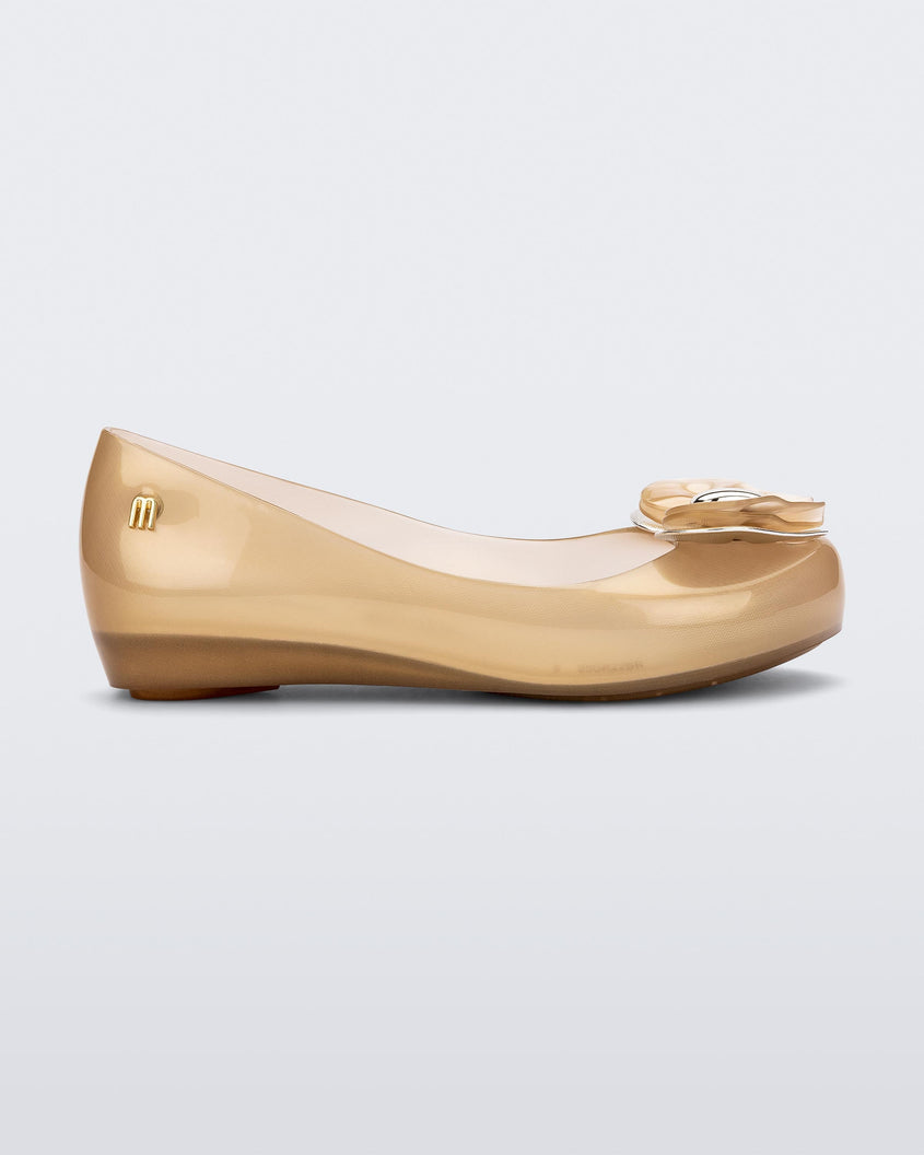Side view of a Pearly Beige Mini Melissa Ultragirl flat with a heart buckle bow detail on the toe.