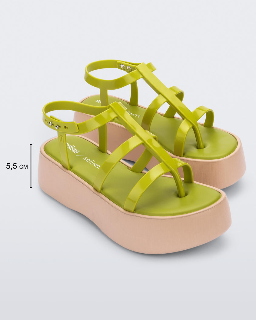 An angled front view of a pair of beige/green Melissa Caribe High Platform sandals with two green front straps joined by a vertical strap intersecting the ankle strap and a beige sole, showing dimensions for the platform height which reads 5.5 centermeters high.