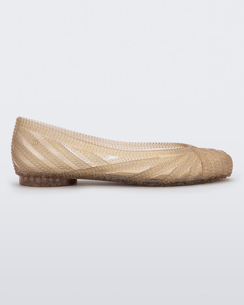Side view of a beige glitter gold Melissa Femme Classy flat with a woven design.