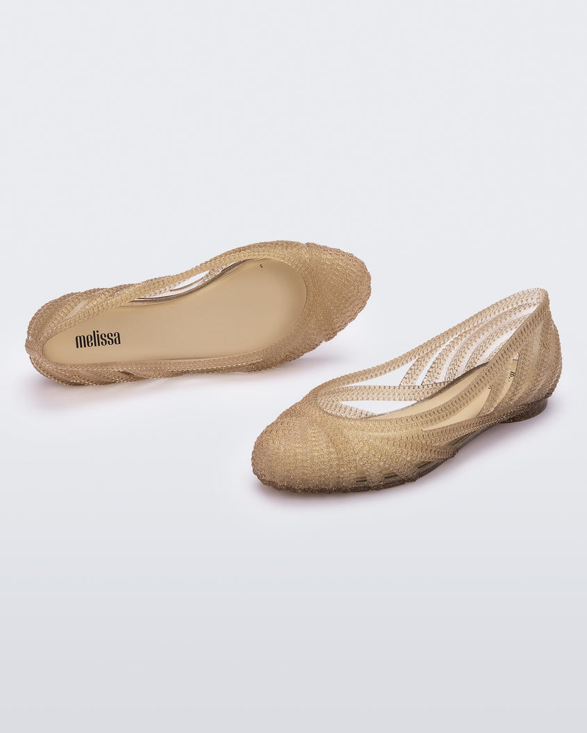 A top and side view of a pair of beige glitter gold Melissa Femme Classy flats with a woven design.