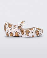 Side view of a Mini Melissa Ultragirl flat in candy print. The print is an all over white / beige chocolate chip cookie print. The shoe has a single velcro strap across the front of the foot. 