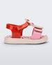 Side view of a pink/red/yellow Mini Melissa Jump Candy sandal with a print of sprinkles on the insole and a plastisol cupcake on top of the straps.
