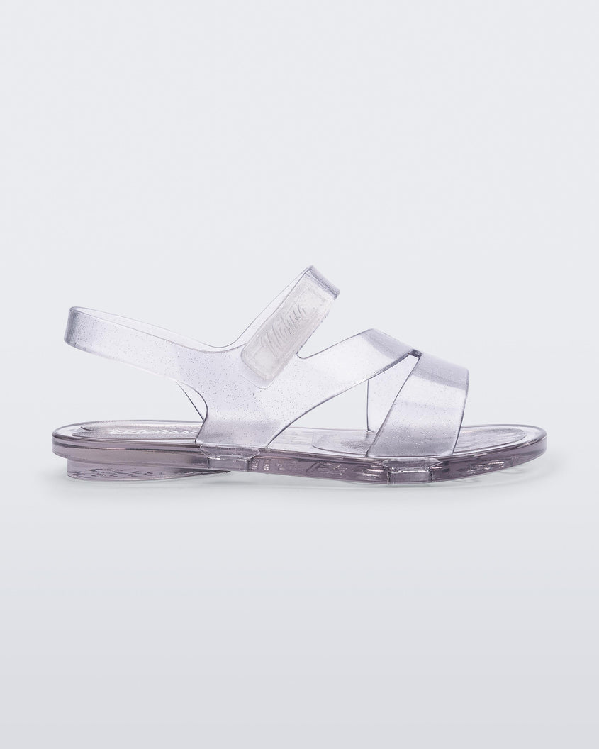 Side view of a clear Mini Melissa The Real Jelly Paris sandal with three front straps and an ankle strap.