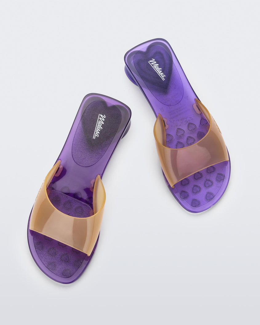Top view of a pair of transparent purple/yellow Melissa Kim slides.