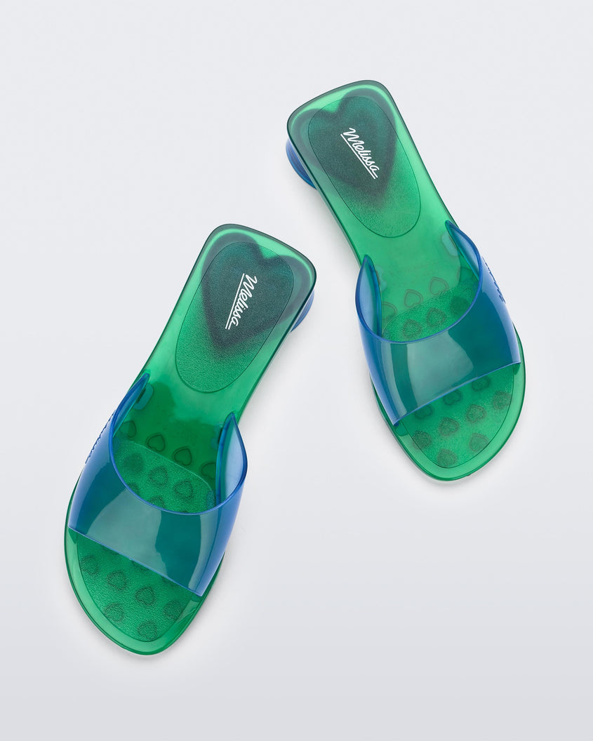 Top view of a pair of transparent blue/green Melissa Kim slides.