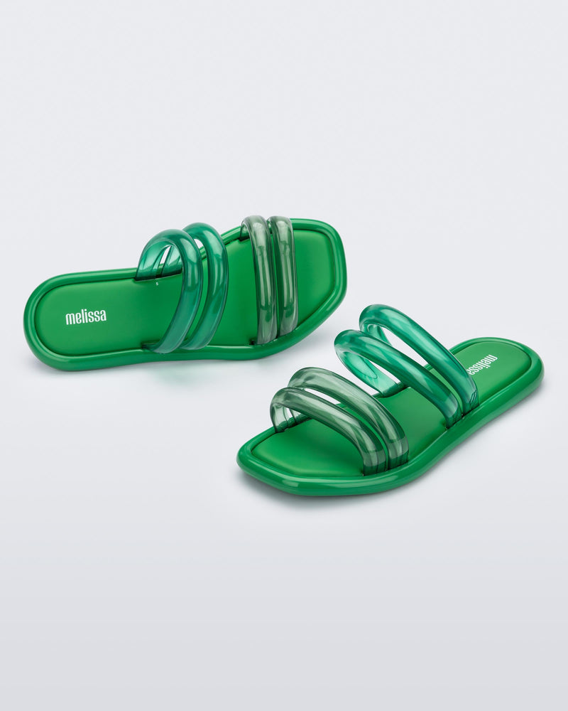 Top and angled view of a pair of  green and transparent green Melissa Airbubble slides.