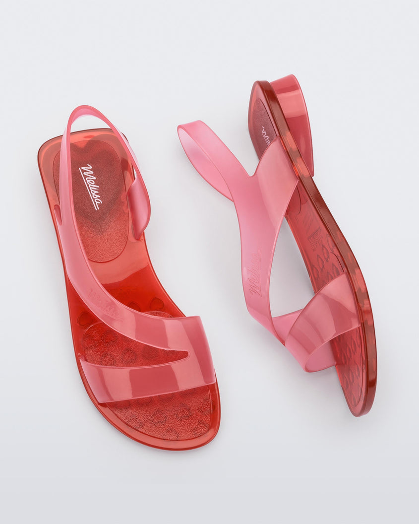 A top and side view of a pair of pink/red Melissa The Real Jelly Paris sandals with two front straps and an ankle strap.