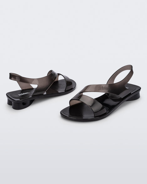 An angled front and side view of a pair of black Melissa The Real Jelly Paris sandals with two front straps and an ankle strap.
