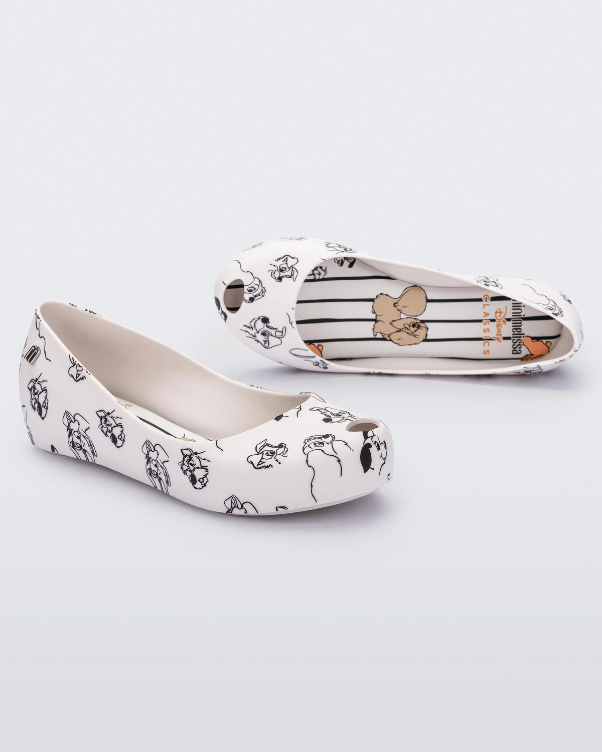 An angled front and side view of a pair of white/grey Mini Melissa Ultragirl Cats & Dogs flats with a white base and cartoon dog face drawing pattern across the base.