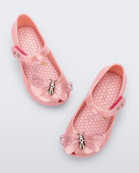 Top view of a pair of pearly pink Mini Melissa Ultragirl Bugs flats with a top strap and a bug detail on the toe.