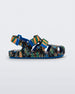 Side view of a blue/green Mini Melissa Yoyo sandal with a black, green and blue patterned base, with two green and orange velcro front straps and an ankle strap.