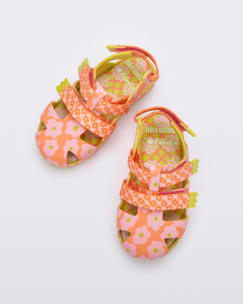 Top view of a pair of Yellow/Orange Mini Melissa Yoyo sandals with orange and pink floral base, 2 front velcro straps, 1 back velcro strap and a yellow sole.
