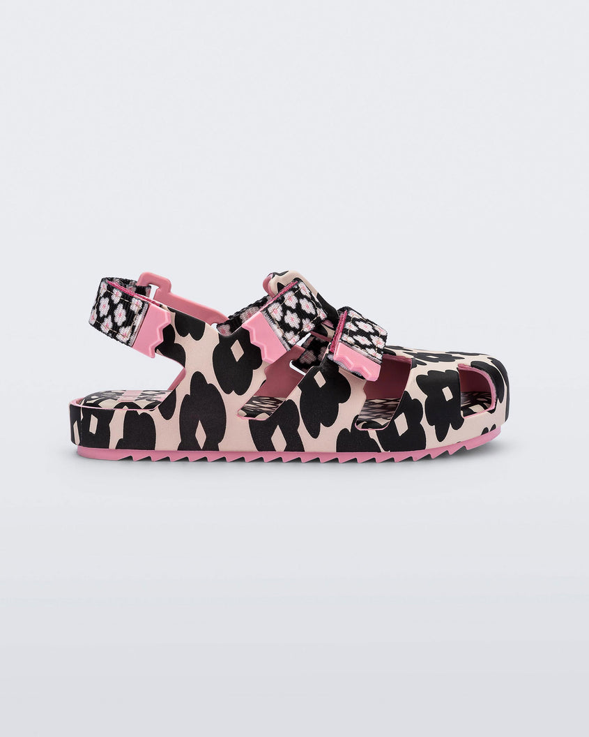 Side view of a pink/black Mini Melissa Yoyo sandal with a pink and black floral base, two velcro front straps and a back ankle strap.