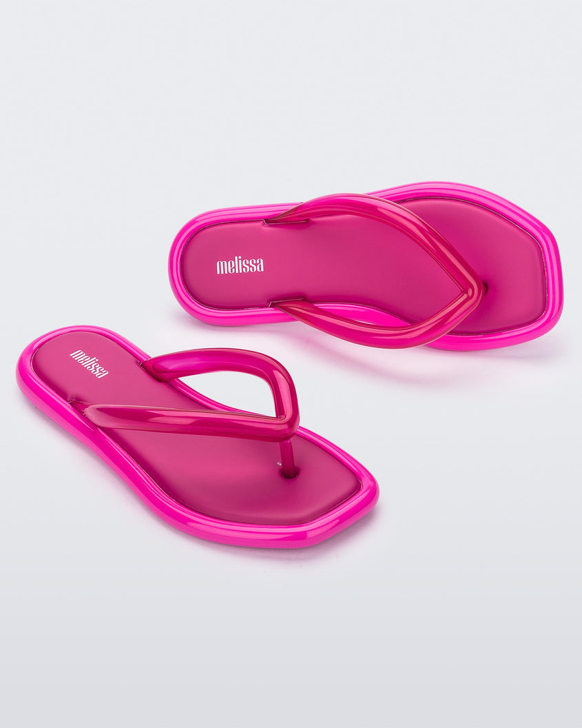 Angled view of a pair of dark pink Melissa Airbubble Flip Flops.