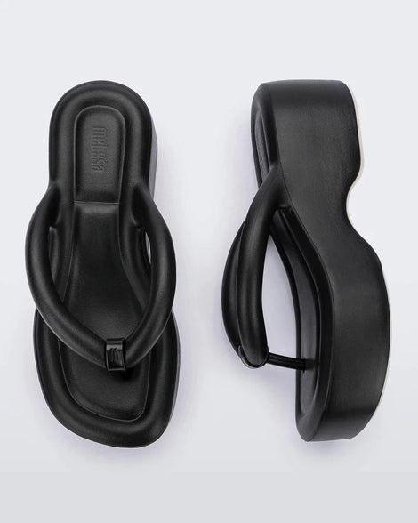 A top and side view of a pair of black Melissa Free Platform flip flops with puffer-like straps.