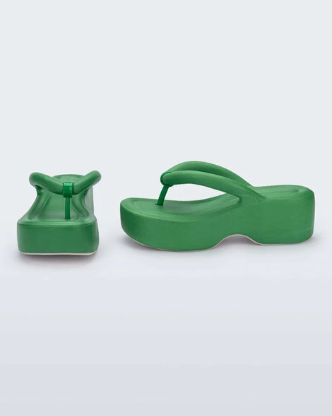 A side and front view of a pair of green Melissa Free Platform flip flops with puffer-like straps.