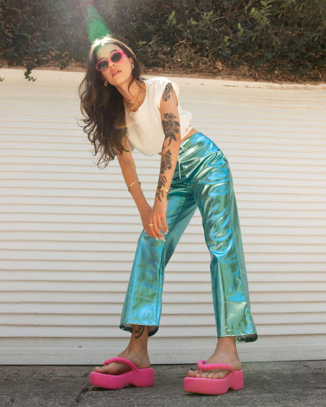 A model posing for a picture wearing a white shirt, blue pants and a pair of pink Melissa Free Platform Flip Flops with puffer-like straps.