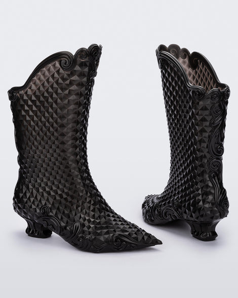 An angled front and back view of a pair of clear black Melissa Court Boots with a short heel, heart detail on the front and a checkered pattern texture.