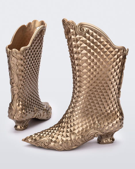 A back and side view of a pair of metallic gold Melissa Court Boots with a short heel, heart detail on the front and a checkered pattern texture.