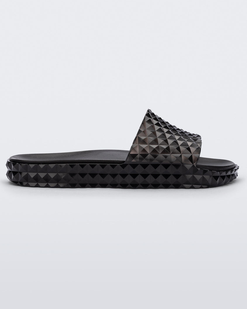 Side view of a transparent black Melissa Court Slide with a checkered pattern texture.