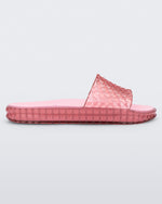 Side view of a transparent pink Melissa Court Slide with a checkered pattern texture.