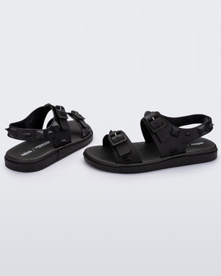 A side and back view of a pair of black Melissa Spikes Sandals with two straps with buckles on top and spike details around the base.