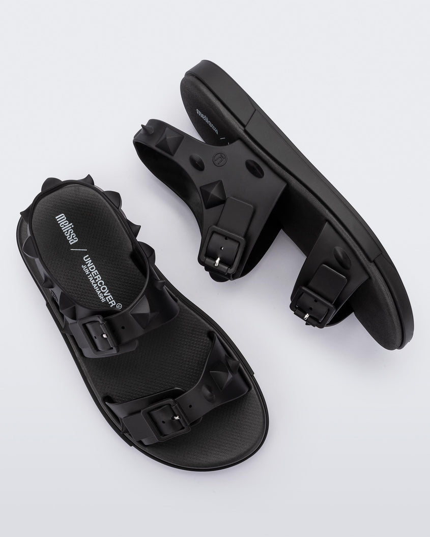 A top and side view of a pair of black Melissa Spikes Sandals with two straps with buckles on top and spike details around the base.