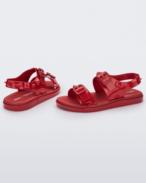 A side and back view of a pair of red Melissa Spikes Sandals with two straps with buckles on top and spike details around the base.