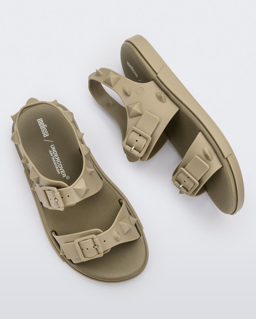 A top and side view of a pair of beige Melissa Spikes Sandals with two straps with buckles on top and spike details around the base.