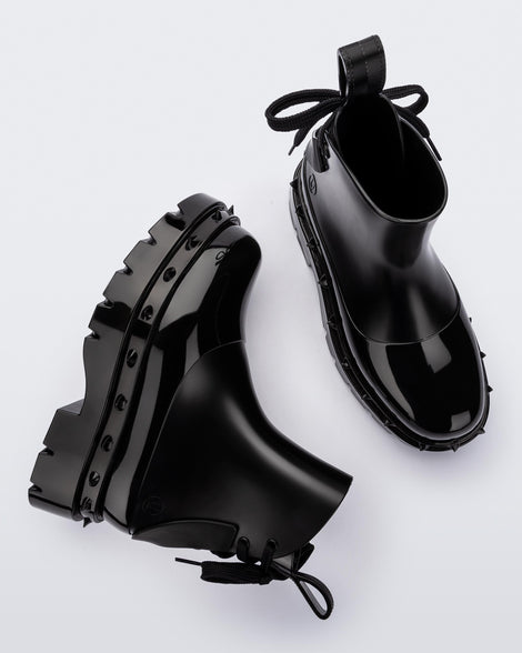A top and side view of a pair of black Melissa Spikes Boots with spike details around the sole and laces in the back.