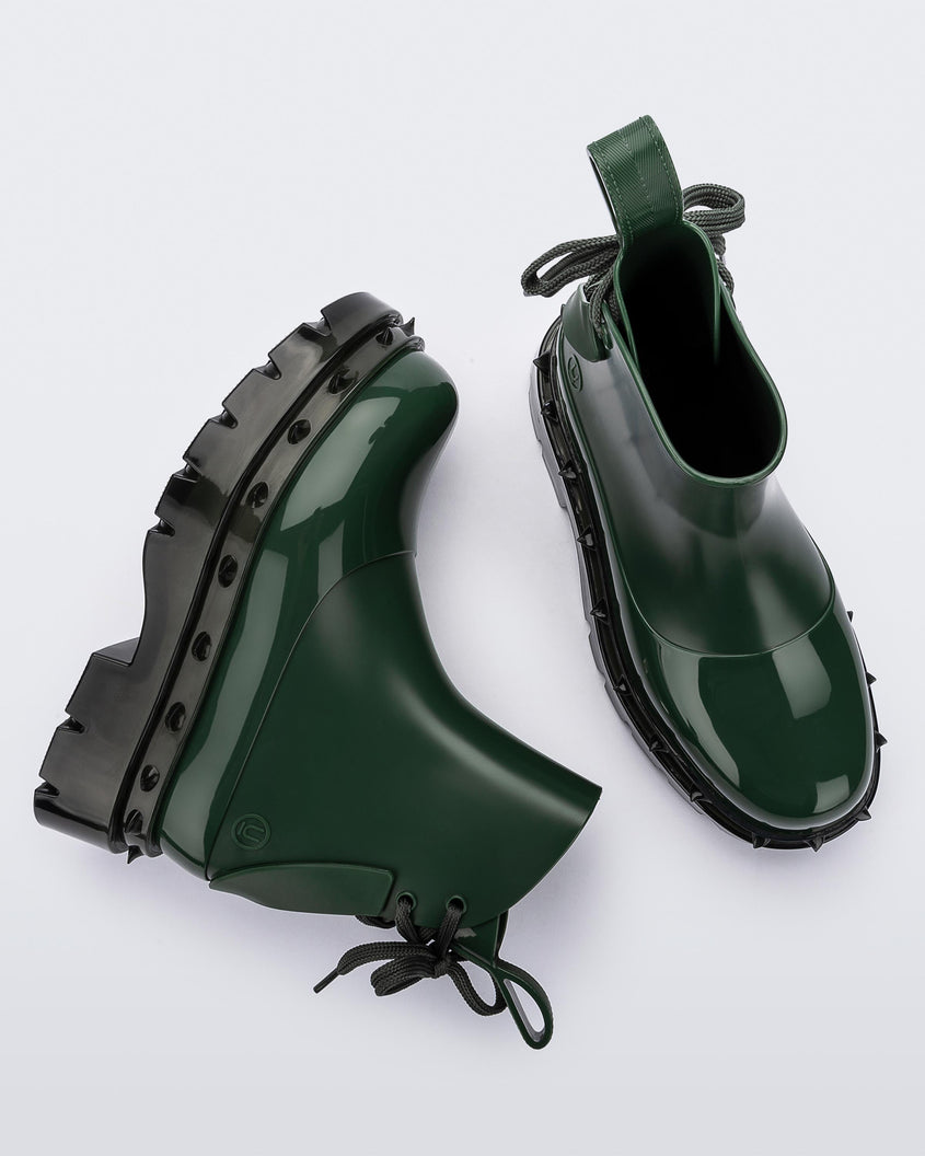 A top and side view of a pair of green Melissa Spikes Boots with spike details around the sole and laces in the back.