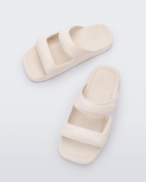 Top view of a pair of beige Melissa Free Grow slides with a square cut out on the front.