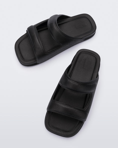 Top view of a pair of black Melissa Free Grow slides with a square cut out on the front.
