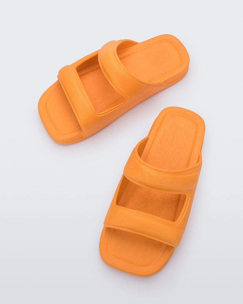 Top view of a pair of orange Melissa Free Grow slides with a square cut out on the front.