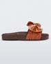 Side view of a Melissa Tie Beach slide with brown sole and brown/orange strap with 3D bow detail. 