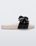 Side view of a Melissa Tie Beach slide with beige sole and beige/black strap with black 3D bow attached. 