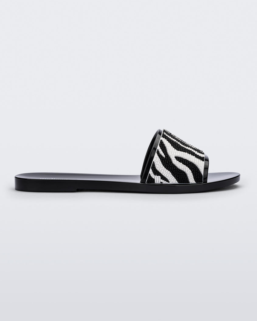 Side view of a black/white Melissa Savage slide with a zebra print on the strap.
