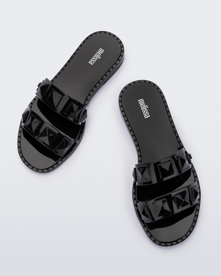 Top view of a pair of black Melissa Lucy slides with stud details on the two straps.