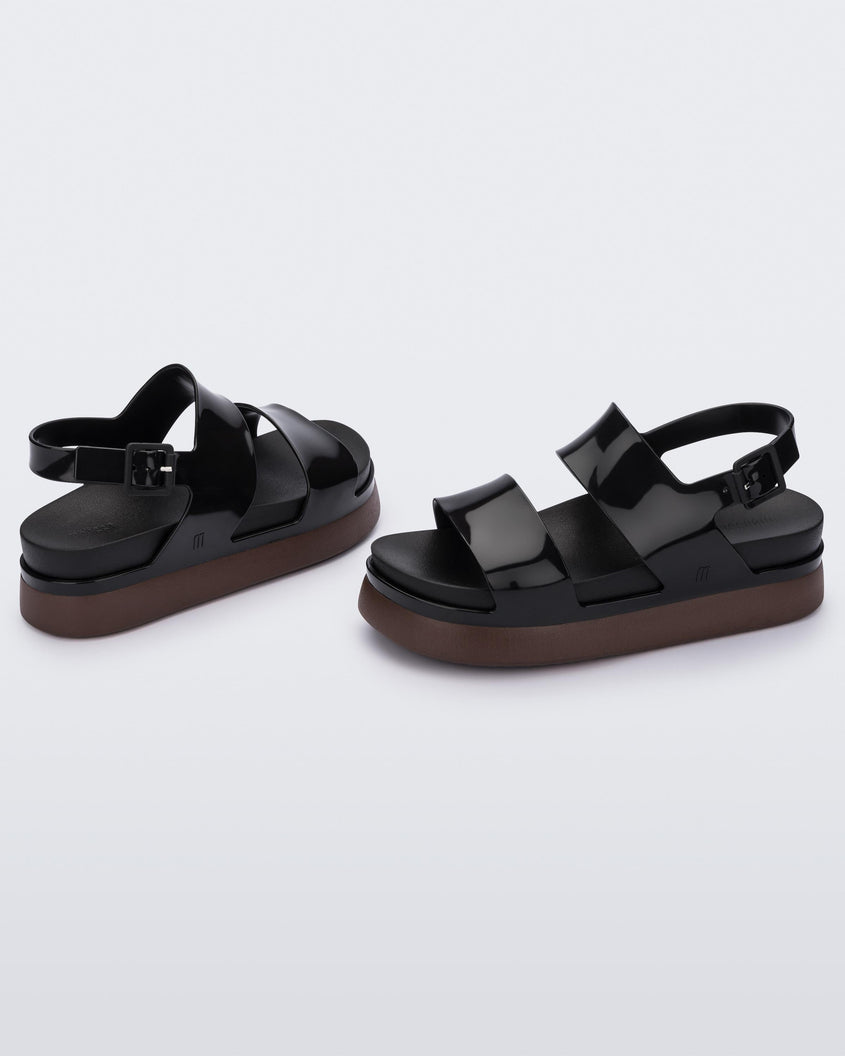 Side view of a pair of black/brown Melissa Cosmic platform sandals with a brown sole and two black straps.