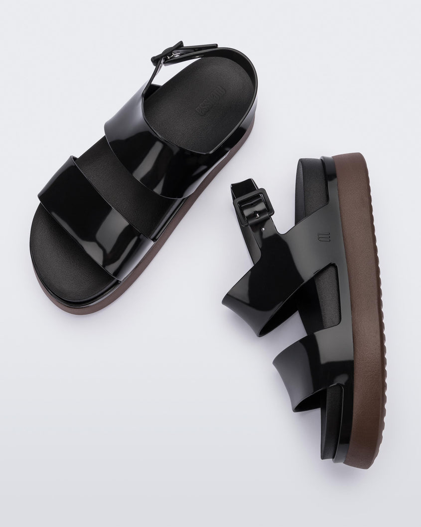 A top and side view of a pair of black/brown Melissa Cosmic platform sandals with a brown sole and two black straps.