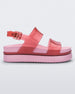 Side view of a transparent red/pink Melissa Cosmic platform sandals with a pink sole and two red straps.