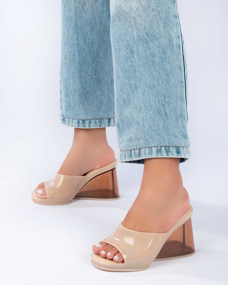 A model's legs wearing a pair of beige Melissa Darling heels with clear soles.