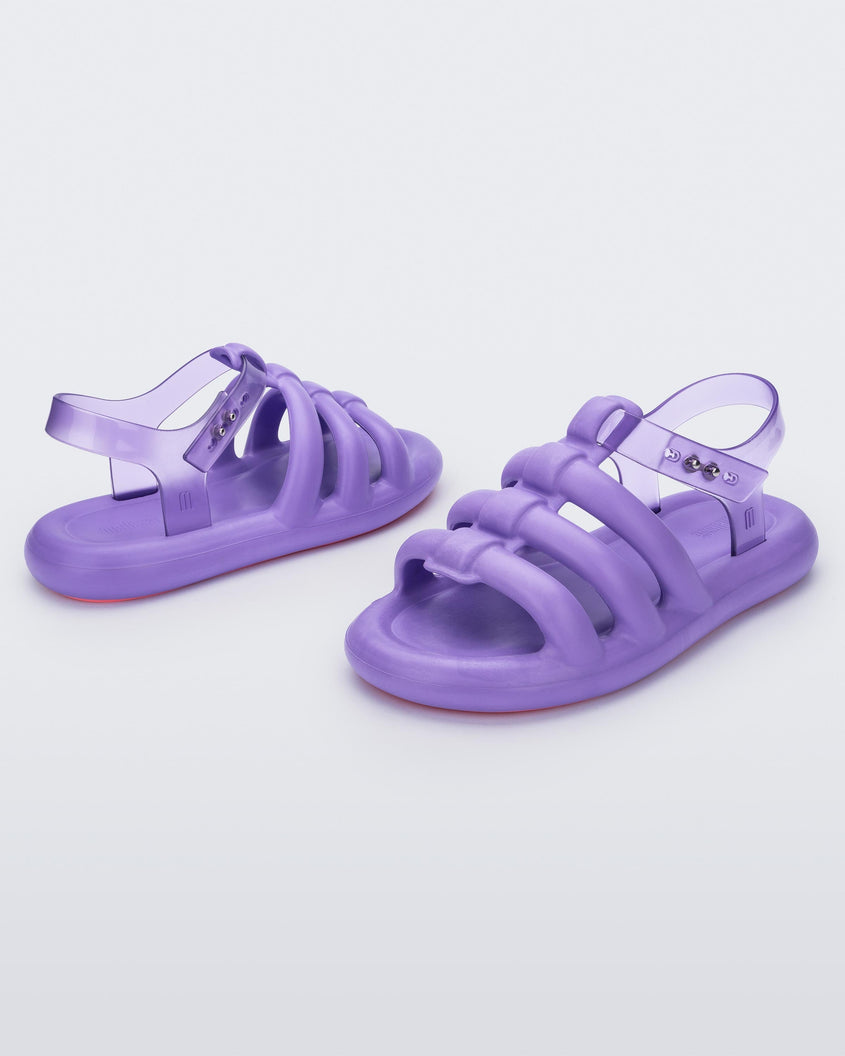 An angled back and front view of a pair of lilac Melissa Freesherman sandals with lilac and clear straps.