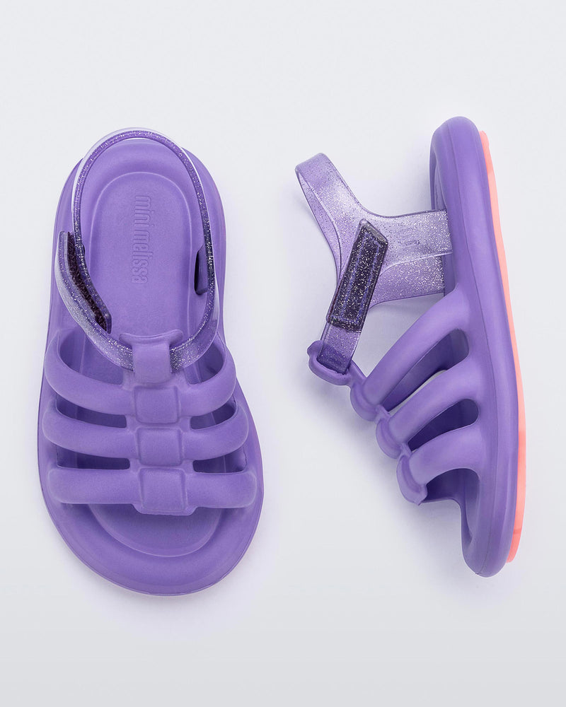 Top and side view of a pair of lilac Mini Melissa Freesherman with lilac and clear glitter straps.