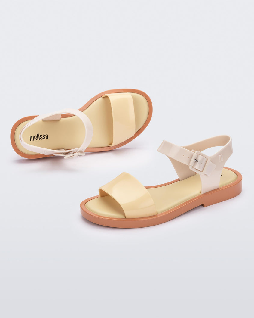 An angled top and side view of a pair of beige/yellow Melissa Mar Sandal with two straps.